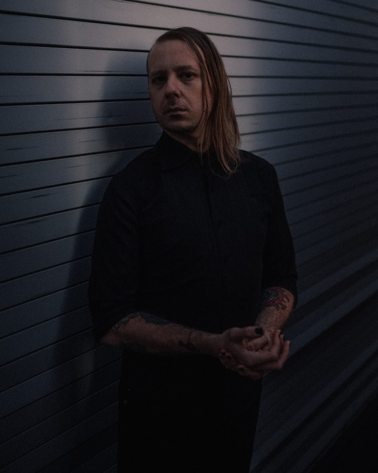 Portrait of Voidova standing against a corrugated industrial wall